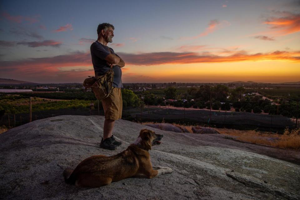 Greg Kirkpatrick, with his dog Ella, take in the sunset at Lindcove Ranch.