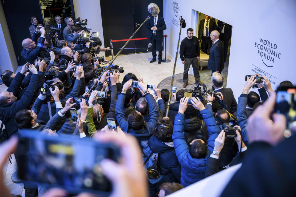 President of Ukraine Volodymyr Zelenskyy stands next to Founder and Executive Chairman of the World Economic Forum Klaus Schwab, top right, in front of the media during the 54th annual meeting of the WEF in Davos, Switzerland, Tuesday, Jan. 16, 2024. (Laurent Gillieron/Keystone via AP)