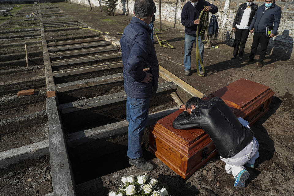 Peruvian migrant Jose Collantes grieves as he cries on the coffin that contains the remains of his wife Silvia Cano, who died due to COVID-19 complications, according to Collantes, at a Catholic cemetery in Santiago, Chile, Friday, July 3, 2020. (AP Photo/Esteban Felix)