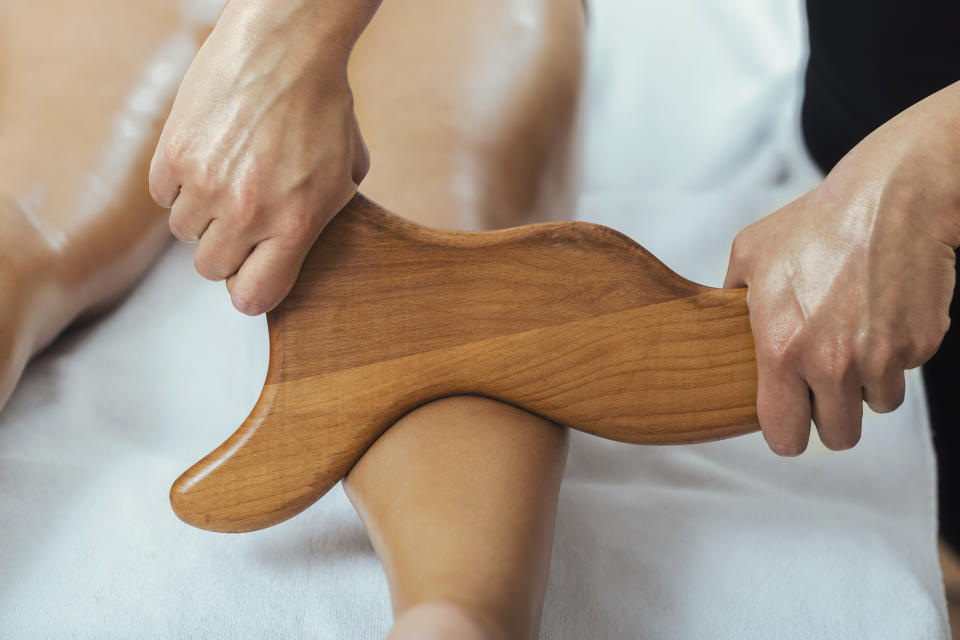 Anti-cellulite maderotherapy massage of female leg calves in a wellness center.