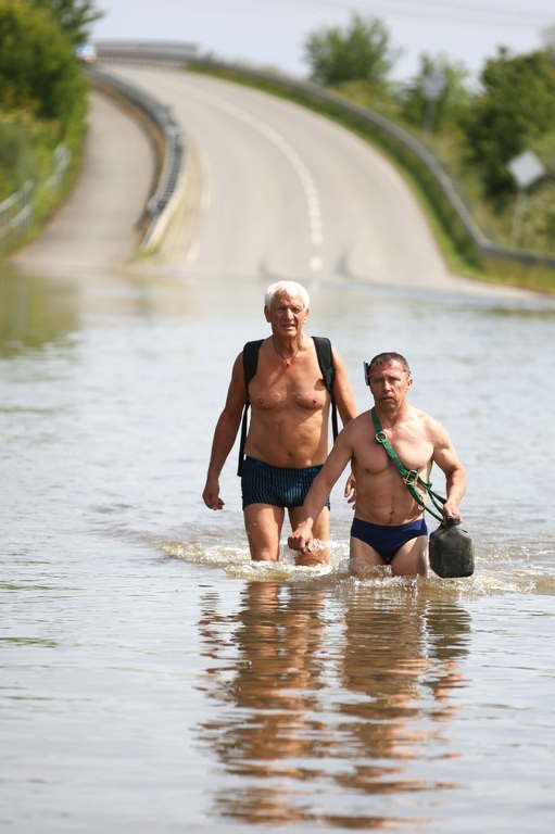 Men walk in underwear through a flooded street to the city of Schoenhausen, eastern Germany on June 11, 2013. Deadly floods forging a path of devastation through central Europe for more than a week bore down on northern Germany Tuesday as troops raced to bolster sodden dykes