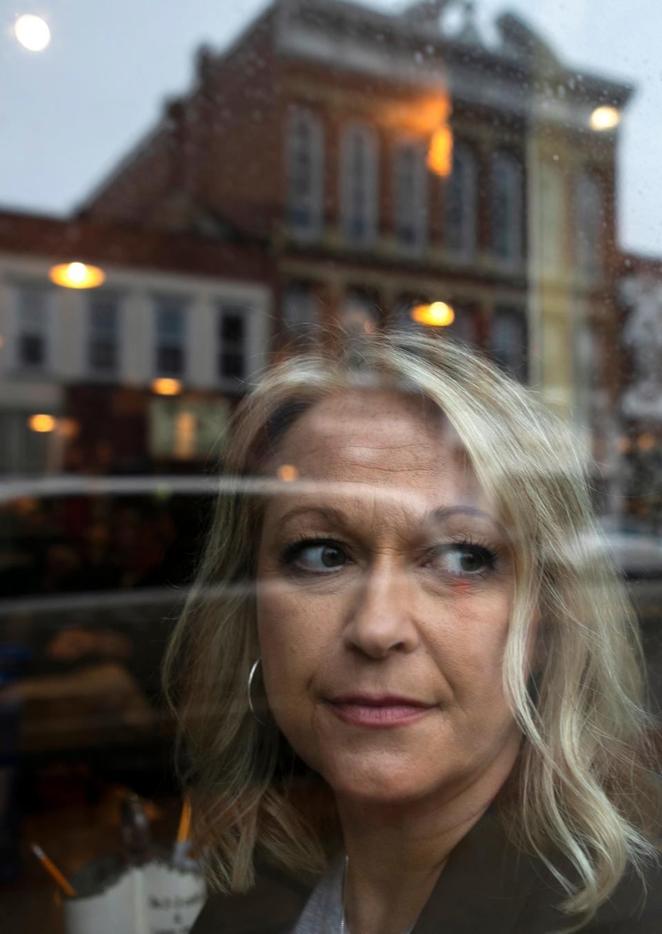 Sarah Haley looks out of the window, as the reflection of downtown Lancaster is caught in the reflection, inside of Art on Main on Mar. 6, 2024, in Lancaster, Ohio. Sarah started the Chase Haley Project, which is a support and education group, after her son died by suicide in 2022.