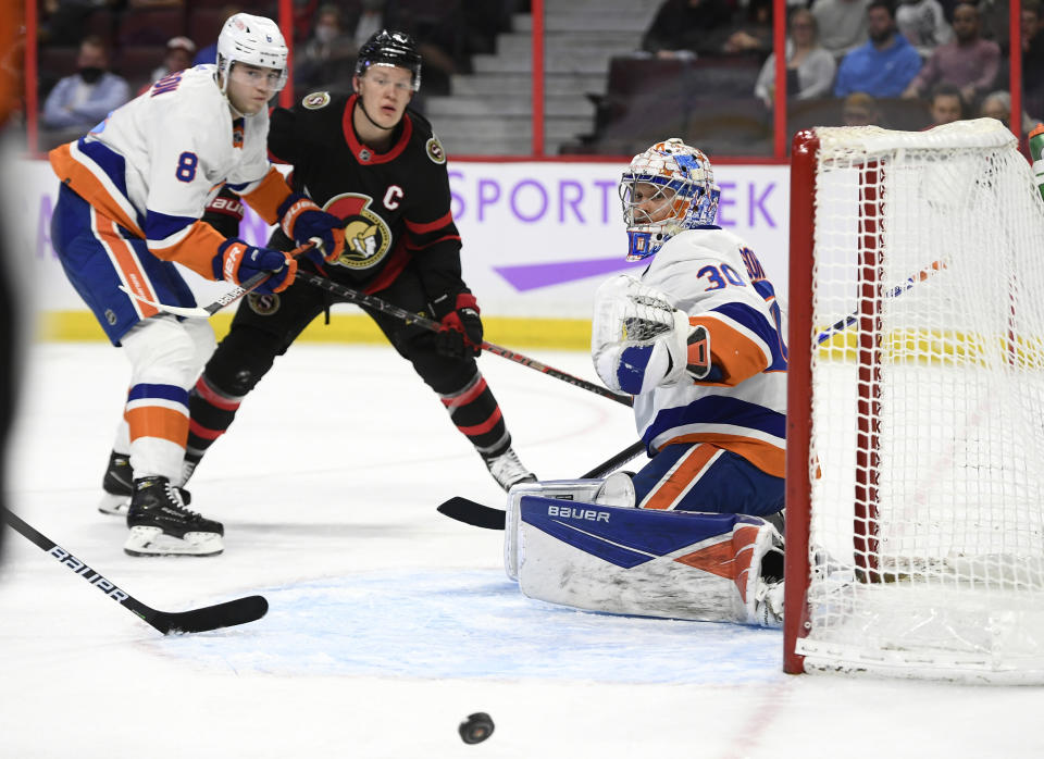 New York Islanders goaltender Ilya Sorokin (30) watches the puck bounce away from him as defenseman Noah Dobson (8) challenges Ottawa Senators left wing Brady Tkachuk (7) during the second period of an NHL hockey game Tuesday, Dec. 7, 2021, in Ottawa, Ontario. (Justin Tang/The Canadian Press via AP)