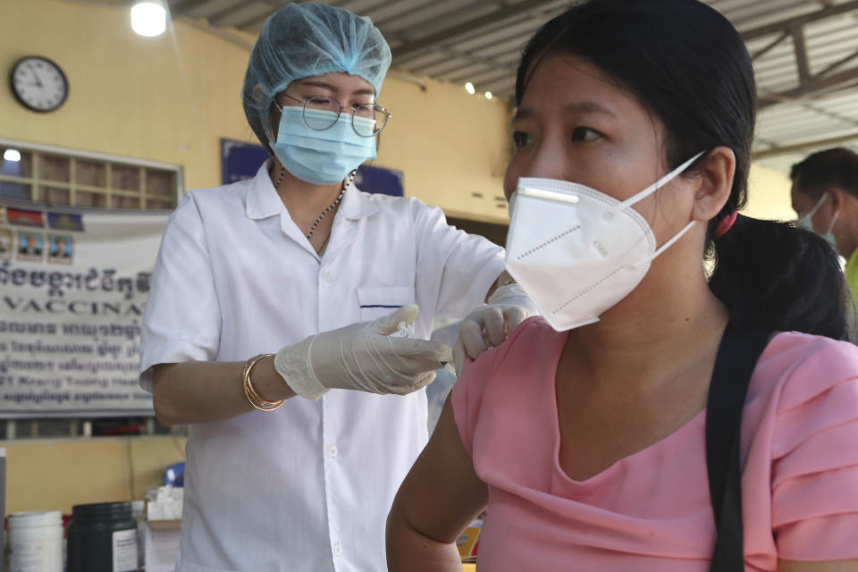 A Cambodian woman, right, receives a shot of fourth dose of the Pfizer's COVID-19 vaccine at a heath center in Phnom Penh, Cambodia, Friday, Jan. 14, 2022. Cambodia on Friday began a fourth round of vaccinations against the coronavirus, following the recent discovery of cases of the omicron variant, with high-risk groups being the first to receive them. (AP Photo/Heng Sinith)