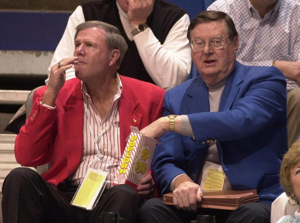 Former UK head coach Joe B. Hall grabs some popcorn from former U of L head coach Denny Crum as they watch a state high school basketball tournament game at Rupp Arena in 2004. The one-time rivals co-hosted a sports talk radio show for almost 11 years together after retiring from coaching.