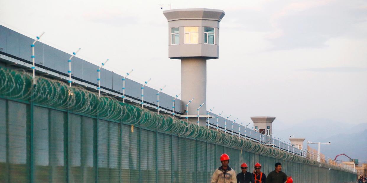 FILE PHOTO: Workers walk by the perimeter fence of what is officially known as a vocational skills education centre in Dabancheng in Xinjiang Uighur Autonomous Region, China September 4, 2018. REUTERS/Thomas Peter/File Photo