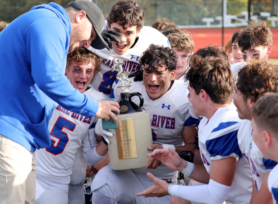 Pearl River quarterback Jack Whelan (5) and Nicholas Espinal and the team celebrate with the Little Brown Jug after they beat Nanuet 20-17 in their football game at Nanuet High School, Oct. 21, 2023.
