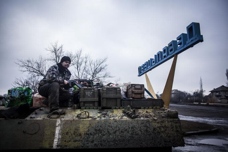 A Ukrainian soldier sits on top of a Ukrainian armored vehicle while resupplying their battalion at the gate of the town of Debaltseve on February 3, 2015