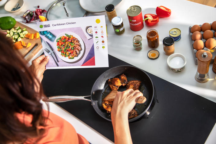 woman making hellofresh meal kit on stove with chicken and vegetables