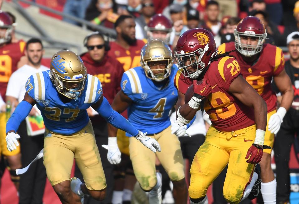 USC running back Keaontay Ingram runs past UCLA Bruins Quentin Lake during their rivalry game at the Los Angeles Memorial Coliseum on Nov. 20, 2021. UCLA won the game, 62-33.