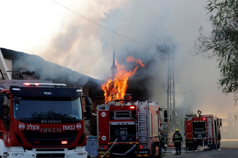 Israeli firefighters work to extinguish a blazing tree after a factory caught on fire in Sderot, southern Israel