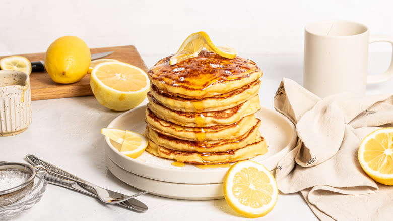 Stack of lemon ricotta pancakes on a plate with lemon slices on top and on the side