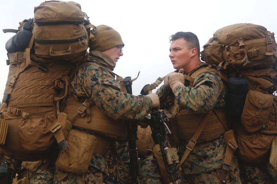 A Marine with the 24th Marine Expeditionary Unit adjusts a fellow Marine’s gear as they prepare to move for a cold-weather training hike inland, Iceland, Oct. 19, 2018,