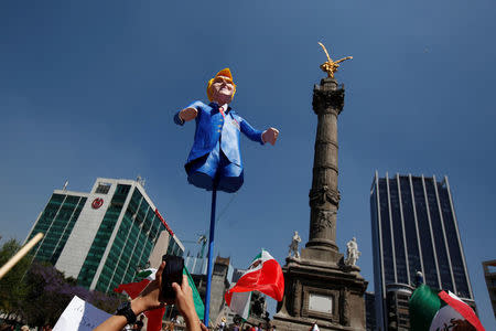 A man holds up an effigy of U.S. President Donald Trump during a march to protest against Trump's proposed border wall and to call for unity, in Mexico City, Mexico, February 12, 2017. REUTERS/Jose Luis Gonzalez