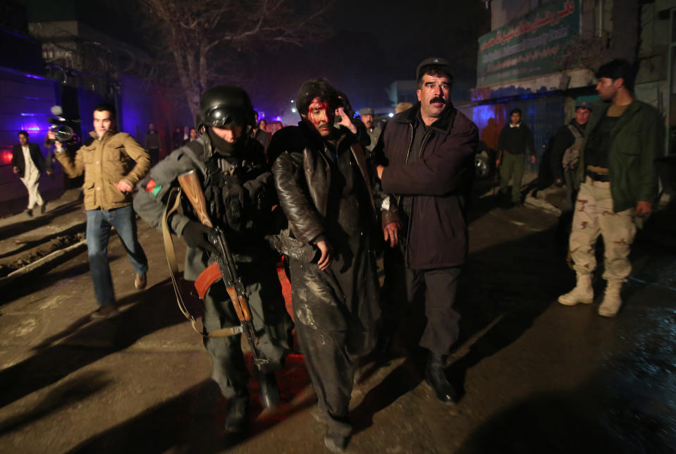 Afghan security forces assist an injured man at the site of an explosion in Kabul, Afghanistan, Friday, Jan. 17, 2014. Afghan police said a suicide bomber attacked a Kabul restaurant popular with foreigners, officials. (AP Photo/Massoud Hossaini)