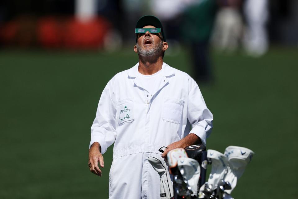 A caddie uses glasses to view the eclipse during a practice round prior to the 2024 Masters Tournament at Augusta National Golf Club in Augusta, Ga.<span class="copyright">Warren Little—Getty Images</span>