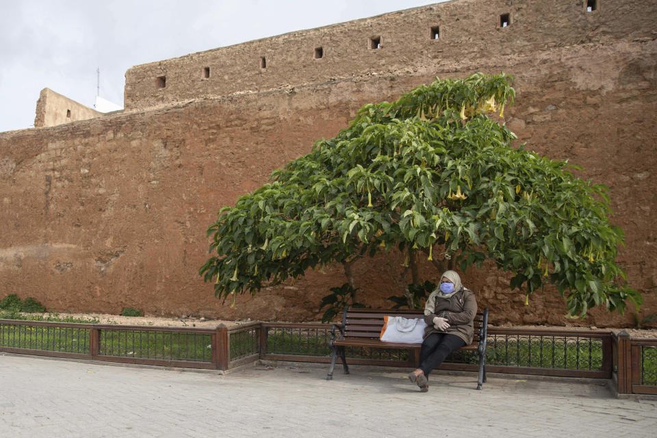 A woman wearing a face mask takes a rest by the walls of the old Medina of Rabat, Morocco, Wednesday, March 18, 2020. For most people, the new coronavirus causes only mild or moderate symptoms, such as fever and cough. For some, especially older adults and people with existing health problems, it can cause more severe illness, including pneumonia. (AP Photo/Mosa'ab Elshamy)