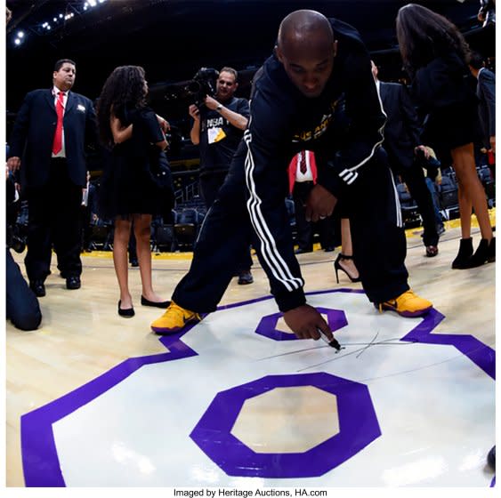 Kobe Bryant signs the No. 8 painted on the Staples Center floor following his final NBA game April 13, 2016.