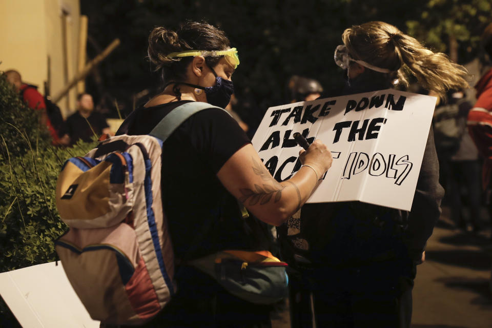 Protesters make signs after protesters tried to topple a statue of Andrew Jackson in Lafayette Park near the White House in Washington, on Monday, June 22, 2020. (AP Photo/Maya Alleruzzo)