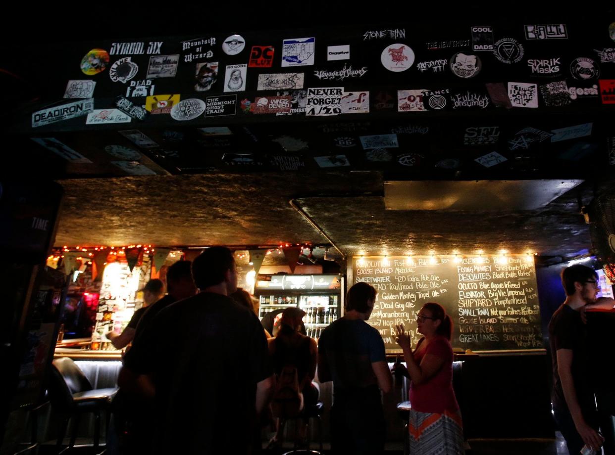 Annabell's customers chat at the Highland Square bar in 2015 in Akron. Stickers of rock bands adorn the walls.