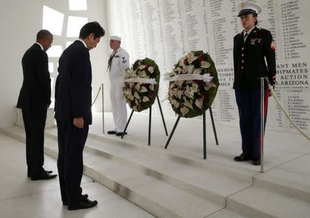 Japanese Prime Minister Shinzo Abe (C) and U.S. President Barack Obama (L) bow their heads during a wreath-laying ceremony aboard the USS Arizona Memorial at Pearl Harbor, Hawaii, U.S., December 27, 2016. REUTERS/Kevin Lamarque