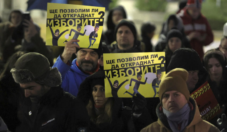 Protesters hold posters that read: "Will we allow them to steal our vote?" as hundreds of Bulgarians gather in front of Bulgarian Parliament on Thursday, Dec. 1, 2022. Hundreds of people attended a street protest in Bulgaria's capital to oppose a revision of the Election Code that reinstates paper ballots, which the previous reformist government had replaced with voting machines. (AP Photo/Valentina Petrova)