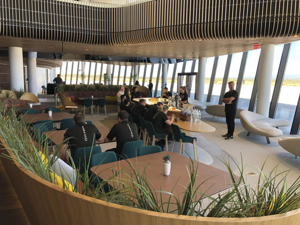 Virgin Galactic employees gather in the ground floor lounge at Spaceport America near Upham, New Mexico, on Thursday, Aug. 15, 2019. Virgin Galactic unveiled some of the interior spaces of the custom-tailored terminal Thursday, saying the designs are aimed at connecting the customers with operations as they prepare for their suborbital flights. (AP Photos/Susan Montoya Bryan)