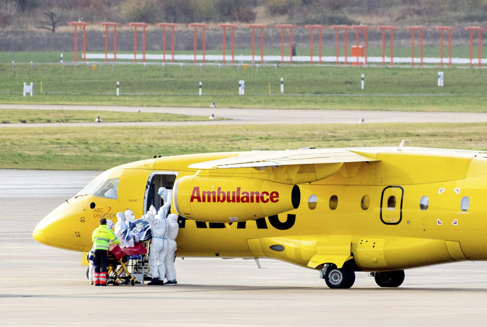 One of two Covid 19 patients is unloaded from a Dornier 328Jet ADAC aircraft by rescue workers at Hanover airport for transfer to hospital by intensive care transport in Langenhagen, Germany, Tuesday, Nov. 30, 2021. Seriously ill patients from intensive care units in Bavaria, Thuringia and Saxony are being transported to areas in the north and west of Germany that are currently less severely affected as part of the "cloverleaf" mechanism coordinated between the federal and state governments throughout Germany. (Hauke-Christian Dittrich/dpa via AP)