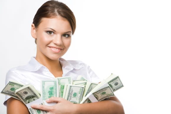 A young smiling woman holding stacks of cash in her arms.