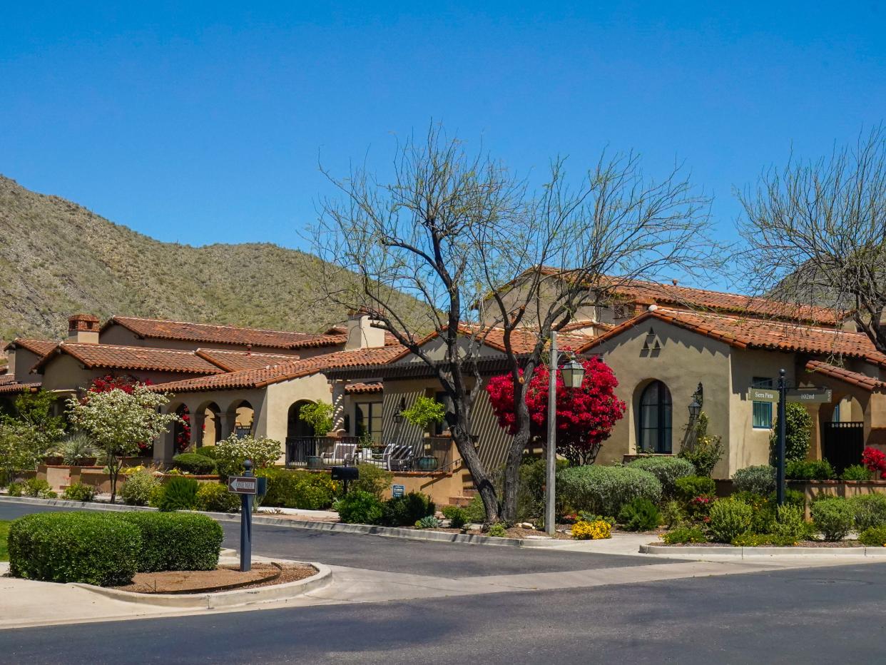 A street lined with luxury homes in front of a mountain with blue skies in the background in Scottsdale