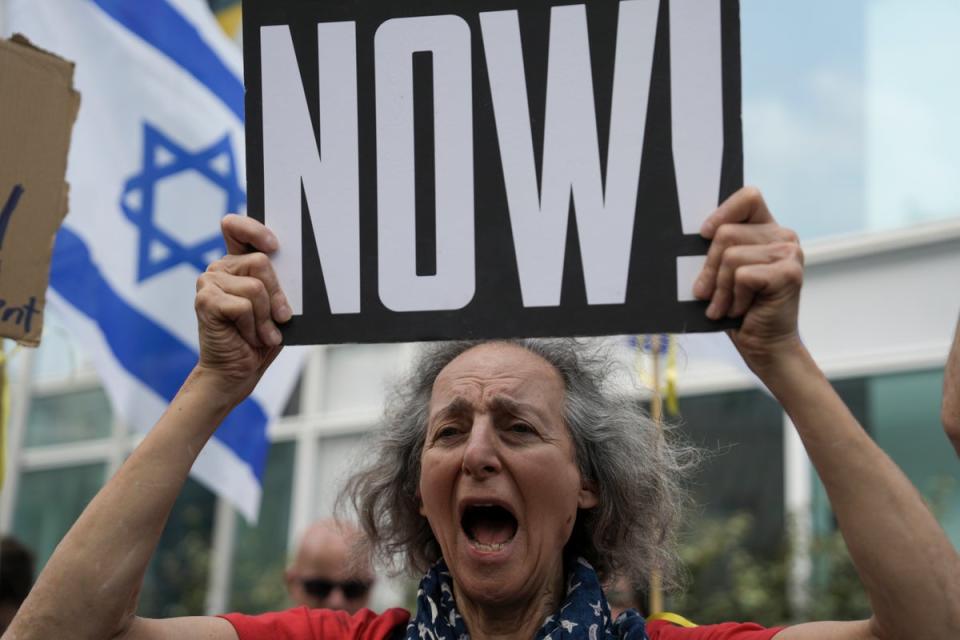 A woman holds a banner and shouts slogans with families and supporters of Israeli hostages held by Hamas in Gaza during a protest calling for their return (AP)