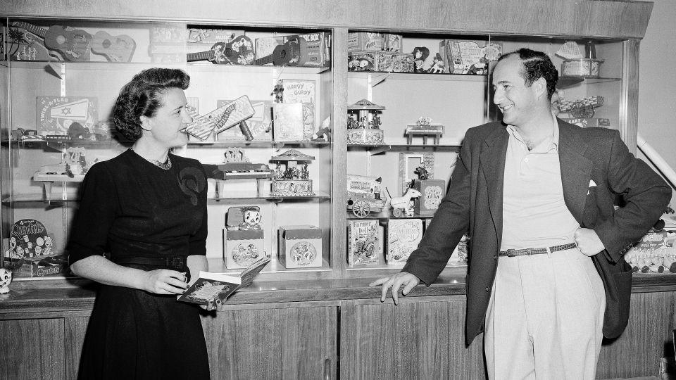 Ruth and Elliot Handler, pose before display case in their office showing toys they have developed in 1951. - AP