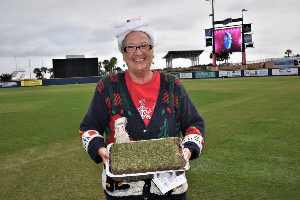 A Blue Wahoos season-ticket holder displays the chunk of sod as keepsake during a pre-removal event at ballpark.