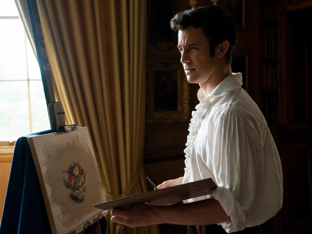 Luke Thompson as Benedict Bridgerton in an episode of "Bridgerton" where Benedict is painting a bowl of fruit while wearing a ruffled shirt.