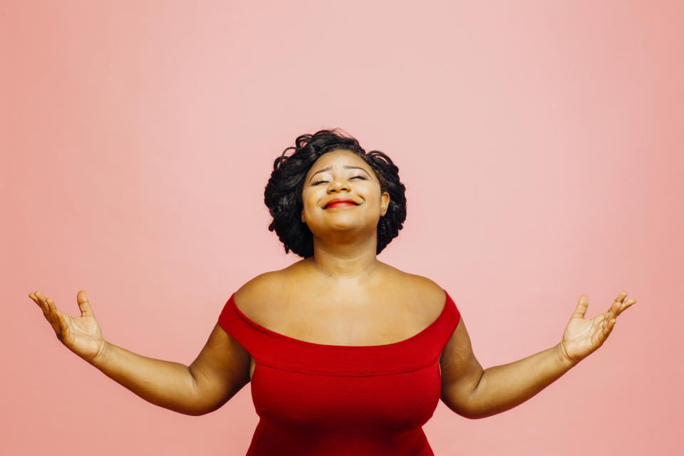 Portrait of a confident, satisfied and happy woman with both hands out, isolated on pink