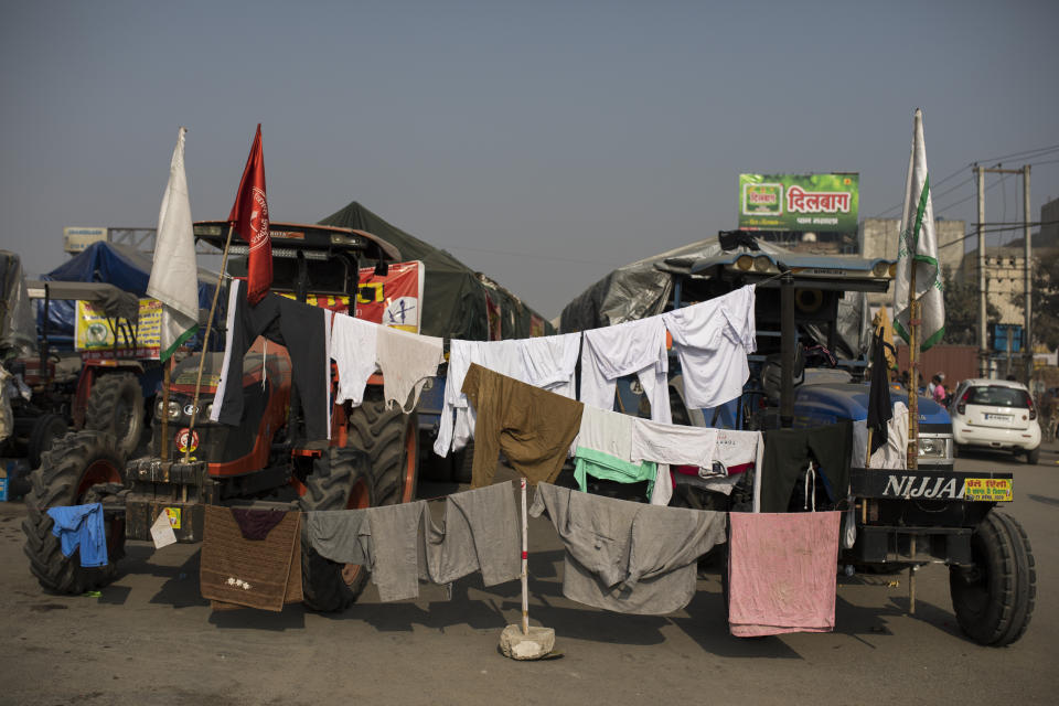 Clothes of protesting farmers hang to dry on lines attached to their tractors as they block a major highway protesting new farming laws they say will result in exploitation by corporations, eventually rendering them landless, at the Delhi-Haryana state border, India, Tuesday, Dec. 1, 2020. The busy, nonstop, arterial highways that connect most northern Indian towns to this city of 29 million people, now beat to the rhythm of never-heard-before cries of “Inquilab Zindabad” (“Long live the revolution”). Tens and thousands of farmers, with colorful distinctive turbans and long, flowing beards, have descended upon its borders where they commandeer wide swathes of roads. (AP Photo/Altaf Qadri)