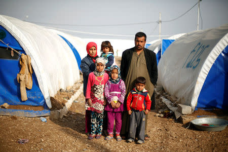 Displaced Iraqi Radwan Sharif, 35, poses for a photograph with his family at Hammam al-Alil camp south of Mosul, Iraq, March 29, 2017. Sharif, a construction worker, said it took him two days to reach the camp with his family from their home in Mosul. It was raining heavily and his wife was scared, he said. Two of his children go to school in the camp. REUTERS/Suhaib Salem