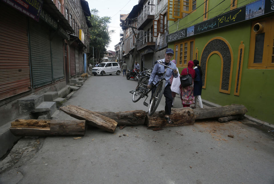 A Kashmiri man crosses a barricade set up by protesters in Srinagar, Indian controlled Kashmir, Wednesday, Aug. 28, 2019. India's government, led by the Hindu nationalist Bharatiya Janata Party, imposed a security lockdown and communications blackout in Muslim-majority Kashmir to avoid a violent reaction to the Aug. 5 decision to downgrade the region's autonomy. The restrictions have been eased slowly, with some businesses reopening, some landline phone service restored and some grade schools holding classes again, though student and teacher attendance has been sparse. (AP Photo/Mukhtar Khan)