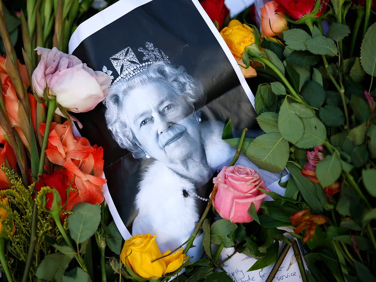 A photograph of Queen Elizabeth II lays among flowers left at a memorial site near Buckingham Palace this weekend (Getty)