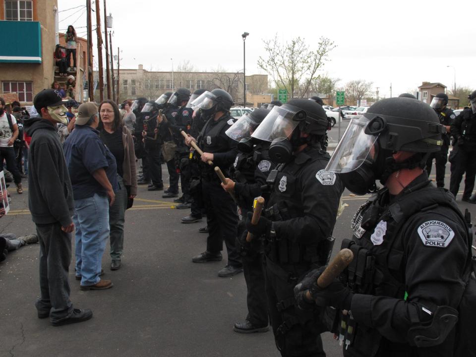 Albuquerque police face off with protesters Sunday, March 30, 2014, in downtown Albuquerque, N.M. during a protest against recent police shootings. Hundreds of protesters marched past riot police in Albuquerque on Sunday, days after a YouTube video emerged threatening retaliation for a recent deadly police shooting. The video, which bore the logo of the computer hacking collective Anonymous, warned of a cyberattack on city websites and called for the protest march. (AP Photo/Russell Contreras)