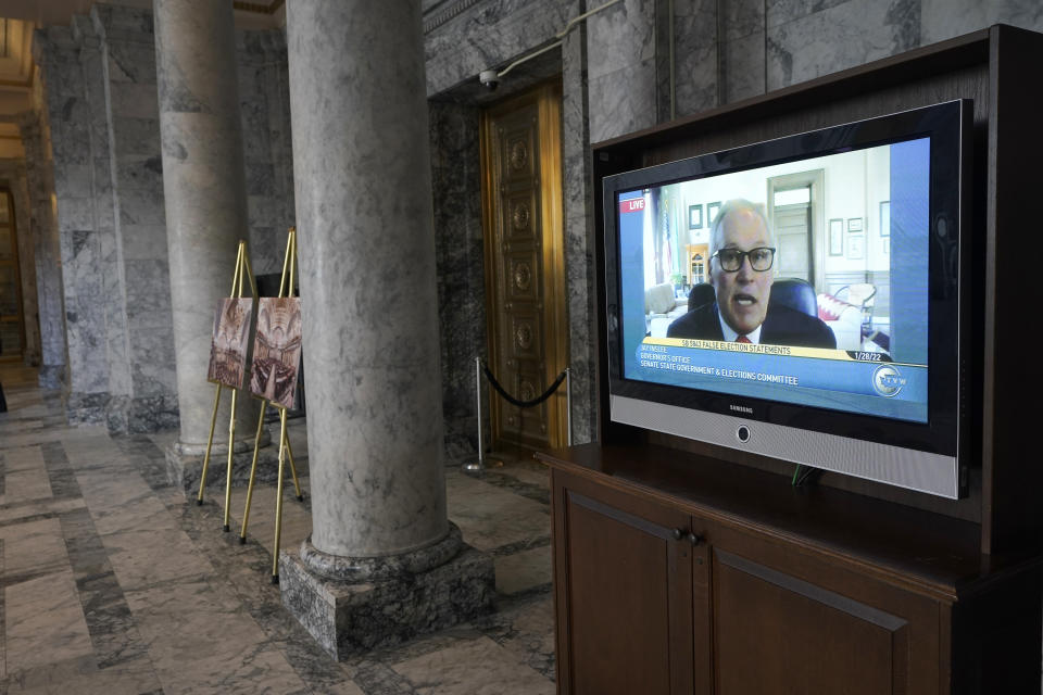 Washington Gov. Jay Inslee is shown on a video monitor outside the Senate chamber as he testifies remotely at a committee hearing on a bill that would make it a gross misdemeanor for elected officials or candidates to knowingly lie about election outcomes if those claims result in violence, Friday, Jan. 28, 2022, at the Capitol in Olympia, Wash. (AP Photo/Ted S. Warren)