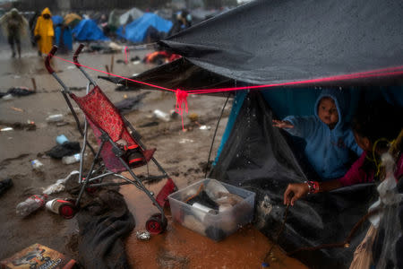 Jonathan, a one-year-old migrant boy from Honduras, part of a caravan of thousands from Central America, gestures towards rainwater dripping from his family's tent while taking refuge at a shelter in Tijuana, Mexico, November 29, 2018. REUTERS/Adrees Latif