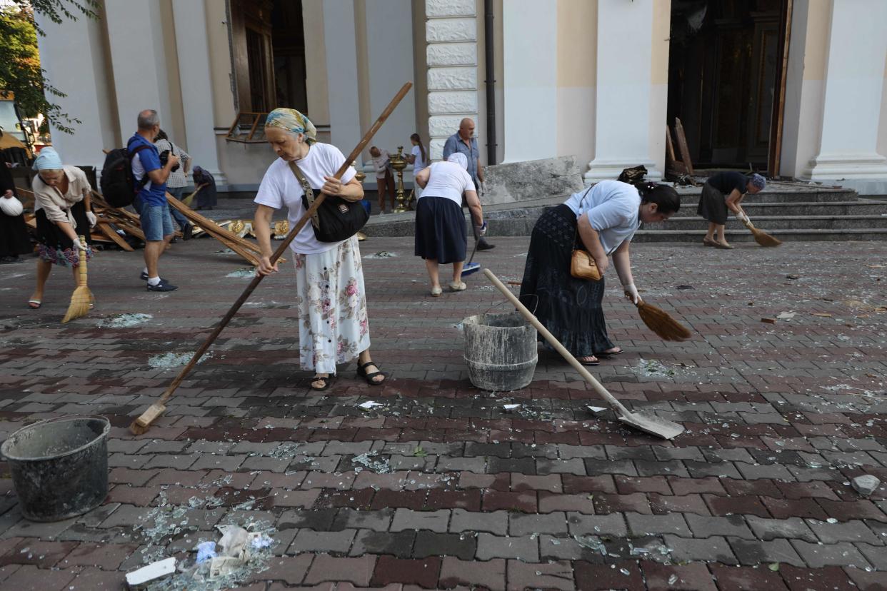 Local residents clean an area outside the damaged Transfiguration Cathedral as a result of a missile strike in Odes (AFP via Getty Images)
