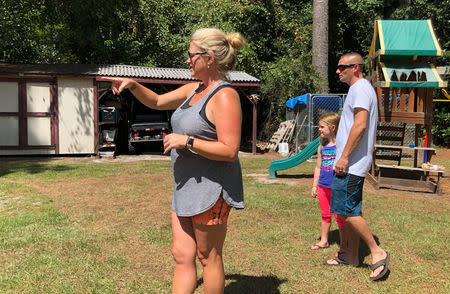 Eve Waddell, daughter Ella, 6, and her husband, acting police chief of Chadbourn, North Carolina, Anthony Spivey, take stock out in the backyard of their home ahead of Hurricane Florence in Fair Bluff, North Carolina, U.S., September 12, 2018. REUTERS/Patrick Rucker