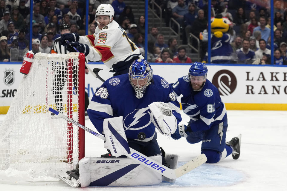 Tampa Bay Lightning goaltender Andrei Vasilevskiy (88) makes a save as defenseman Erik Cernak (81) and Florida Panthers left wing Matthew Tkachuk (19) look on during the third period of an NHL hockey game Wednesday, Dec. 27, 2023, in Tampa, Fla. (AP Photo/Chris O'Meara)