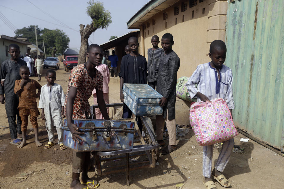 Habubakar Liti, left, Bello Ibrahim, centre, and Isah Nasir, recently released students, arrive back home carrying boxes containing their school belongings in Ketare, Nigeria, Saturday Dec. 19, 2020. Nigeria's freed schoolboys have reunited with their joyful parents after being held captive for nearly a week by gunmen allied with jihadist rebels in the country's northwest. Relieved parents hugged their sons tightly on Saturday in Kankara, where more than 340 boys were abducted from the Government Science Secondary school on the night of Dec. 11. (AP Photo/Sunday Alamba)