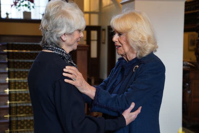 Queen Camilla embracing Diana Parkes as they greet one another