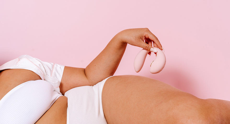 Woman holding Tiff sex toy against a pink background