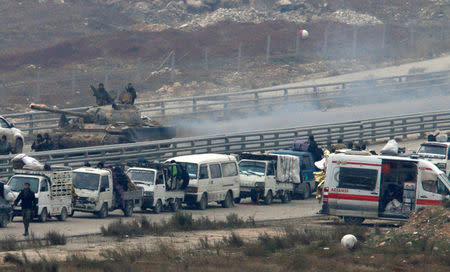 Forces loyal to Syria's President Bashar al-Assad sit on a tank as a convoy of buses and other vehicles bringing people out of eastern Aleppo turns back in the direction of the besieged rebel enclave, Syria December 16, 2016. REUTERS/Omar Sanadiki