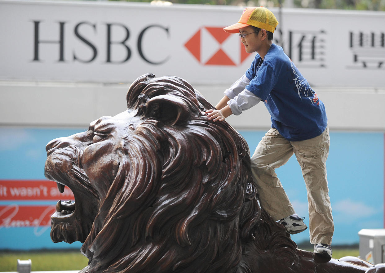 A boy plays on one of the two lions guarding the HSBC bank headquarters in the Central district of Hong Kong on March 3, 2008.  HSBC and its unit Hang Seng Bank are due to announce the 2007 annual results after the stock market close later in the day. AFP PHOTO/MIKE CLARKE (Photo credit should read MIKE CLARKE/AFP via Getty Images)